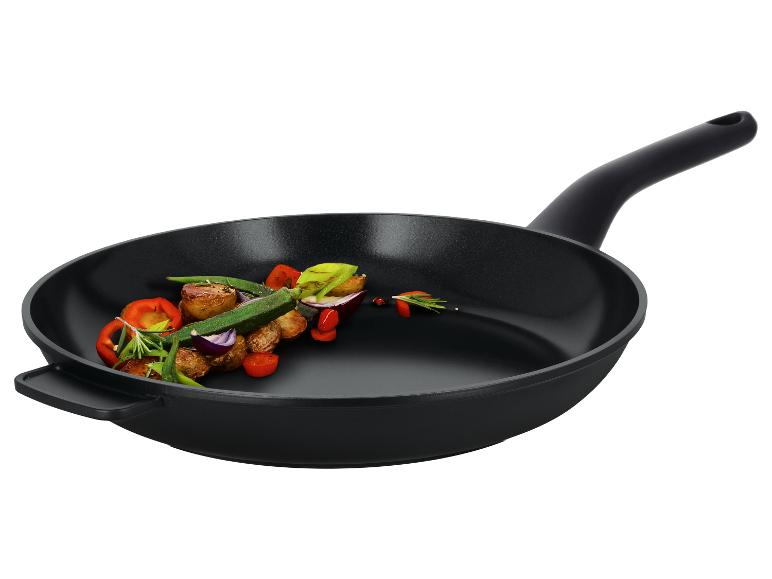 Poêle à frire noire avec des légumes rôtis et des herbes