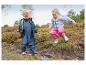 Deux enfants joyeux en cirés et bottes de pluie jouent dans la boue.
