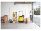 Balayeuse jaune dans un garage avec des outils de jardin et une table pliante.