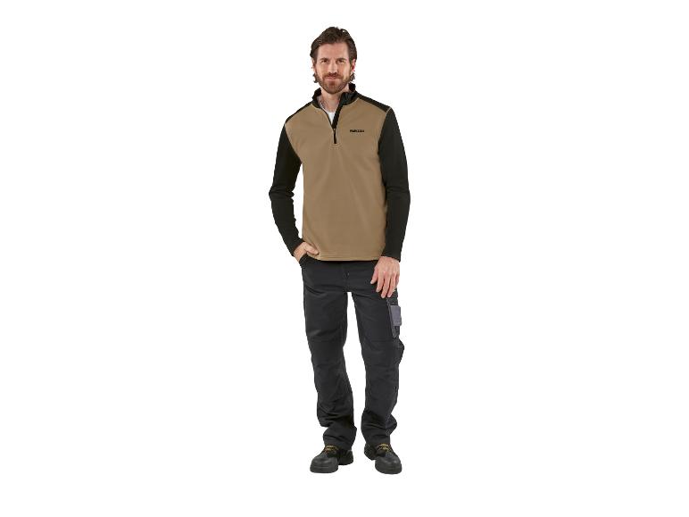 Homme portant un pull Parkside beige et noir et un pantalon de travail noir.