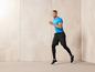 Un homme en t-shirt bleu et short et chaussures de sport noirs, court.