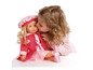 Une petite fille embrasse une poupée vêtue d'une robe rose et aux cheveux blonds.
