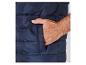 Une veste matelassée bleu marine avec une main dans la poche.