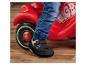 Enfant en jean et chaussures avec protection sur un porteur rouge.