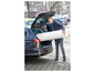 Un homme charge un matelas dans le coffre d'une voiture.