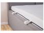 Matelas avec housse blanche et fermeture éclair grise sur un lit rembourré.