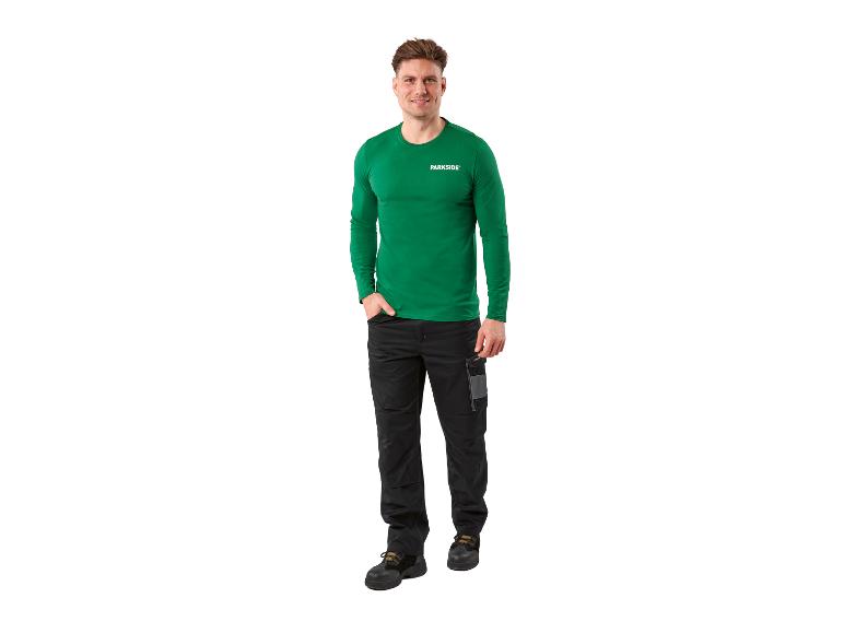 Homme en chemise verte et pantalon de travail noir
