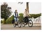 Deux personnes à vélo électrique dans la rue, une femme sur un vélo clair et un homme sur un vélo foncé.