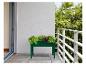 Une jardinière verte avec des herbes sur un balcon.