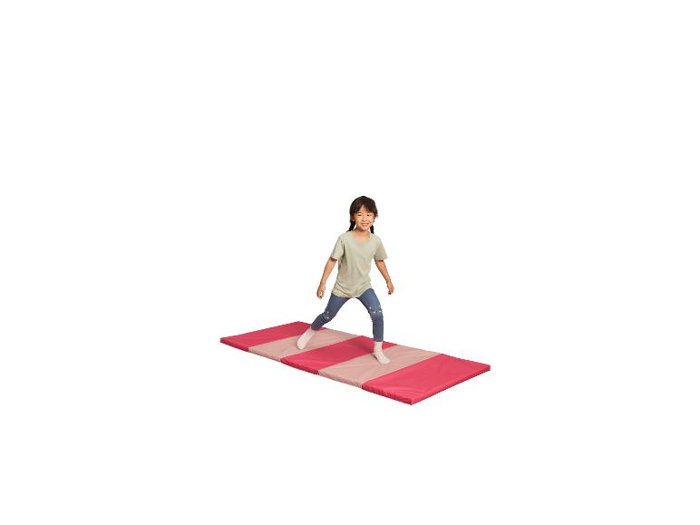 Fille s'exerçant sur un tapis de gymnastique rose et beige.