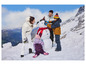 Une famille en manteaux d'hiver construisant un bonhomme de neige dans les montagnes.