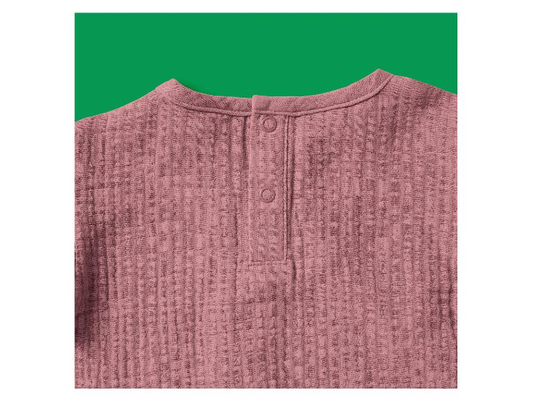 Chemisier en mousseline rose avec boutons à l'arrière du cou, sur fond vert.