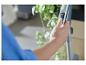 Main d'une personne ajustant les réglages d'un aspirateur, avec une plante en arrière-plan.