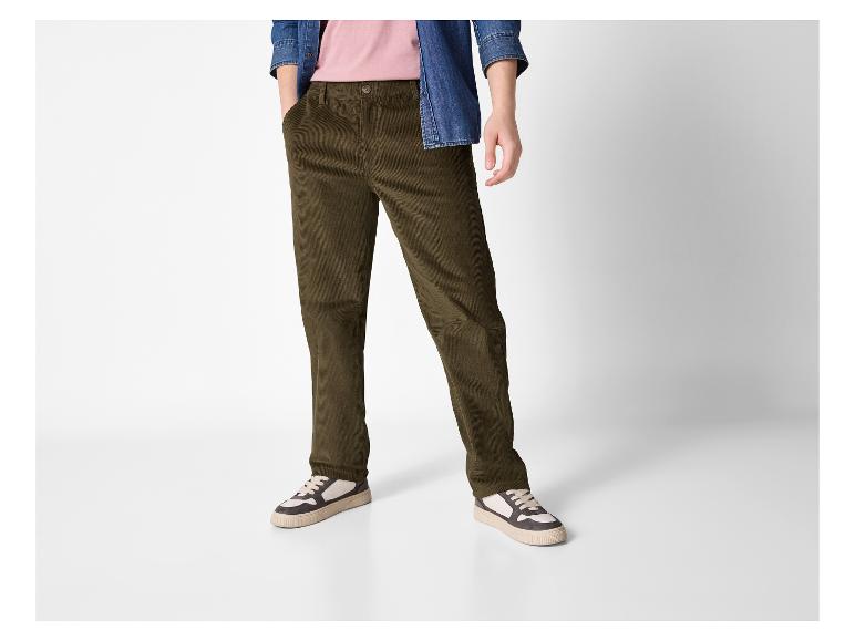 Homme en pantalon de velours côtelé marron, t-shirt rose et chemise en jean.