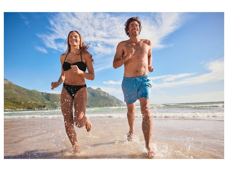 Couple courant sur la plage en maillots de bain.