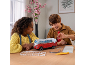 Des enfants assemblent un puzzle 3D de van rouge et blanc sur une table.