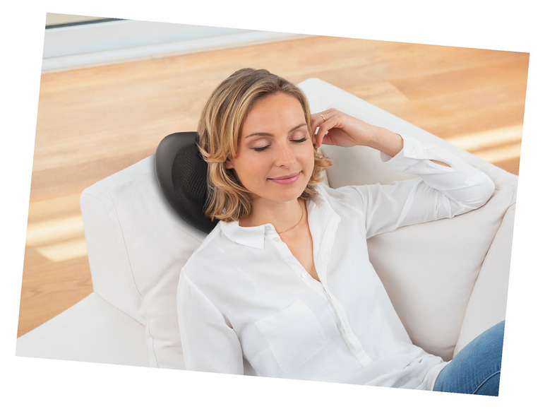Une femme profite d'un coussin de massage sur le canapé.