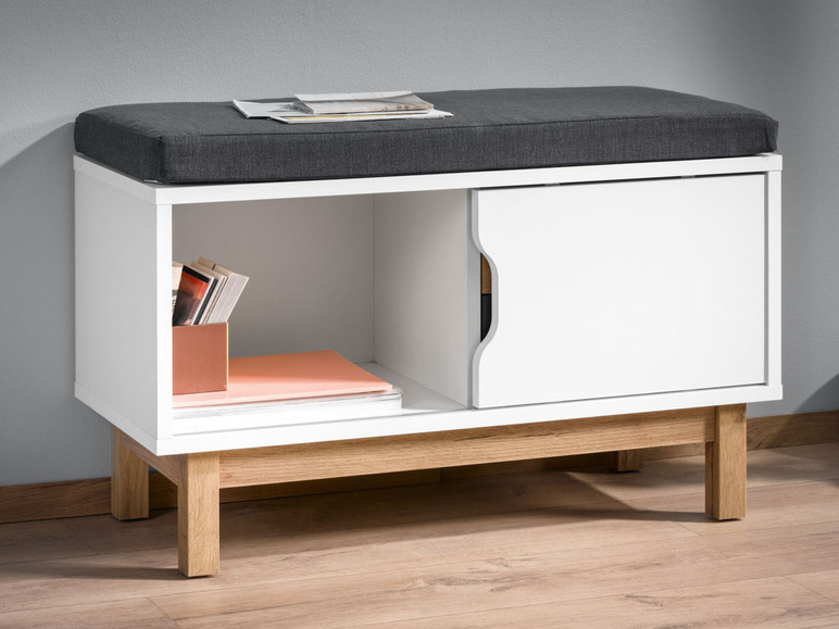 Banc de rangement blanc avec un coussin gris et des pieds en bois.
