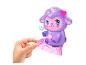 Une peluche violette en forme de mouton avec une corne de licorne et une baguette, tenue par une main.