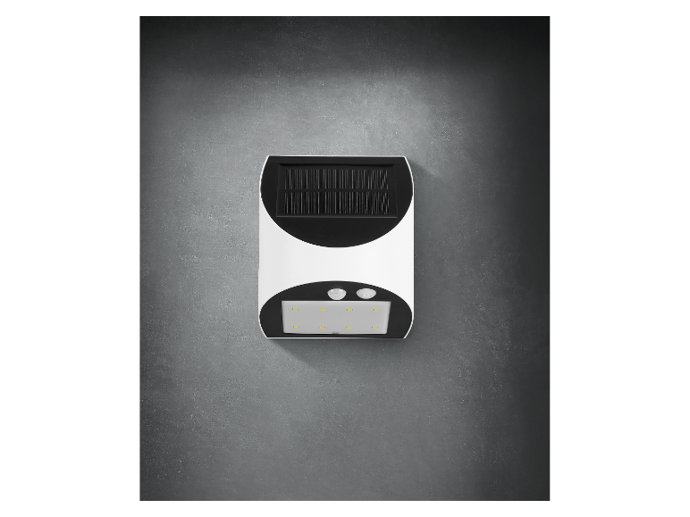 Un luminaire solaire avec détecteur de mouvement fixé à un mur gris.