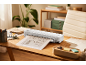 Une plastifieuse blanche sur un bureau en bois plastifiant le plan d'une maison.
