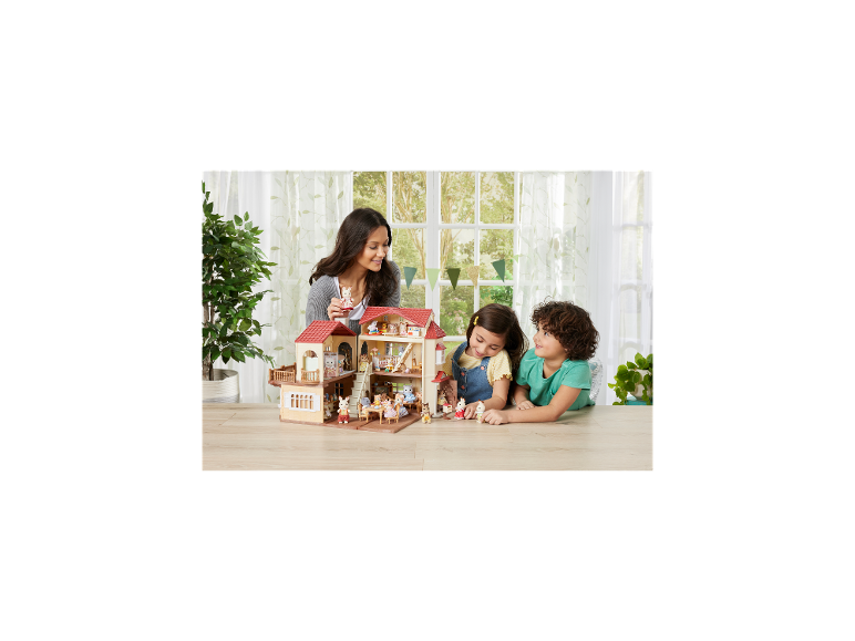 Femme et enfants jouant avec une maison de poupée et des figurines d'animaux.