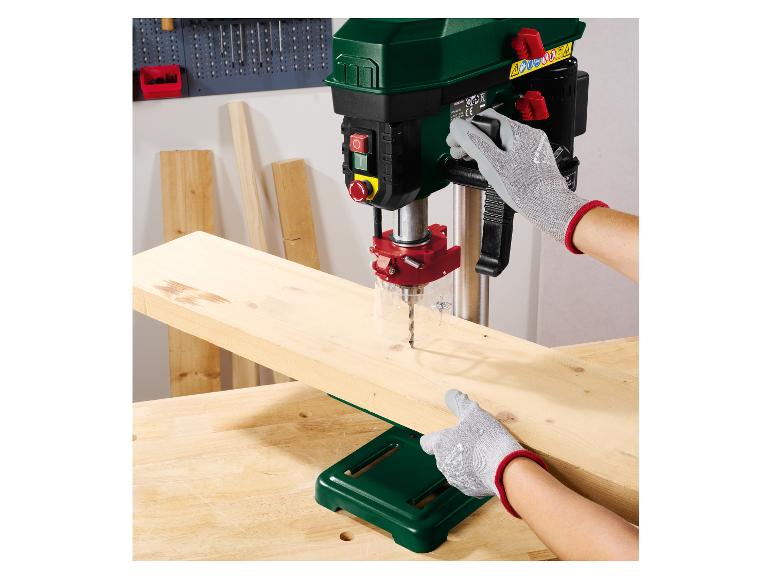 Personne utilisant une perceuse à colonne Parkside pour percer une planche en bois.