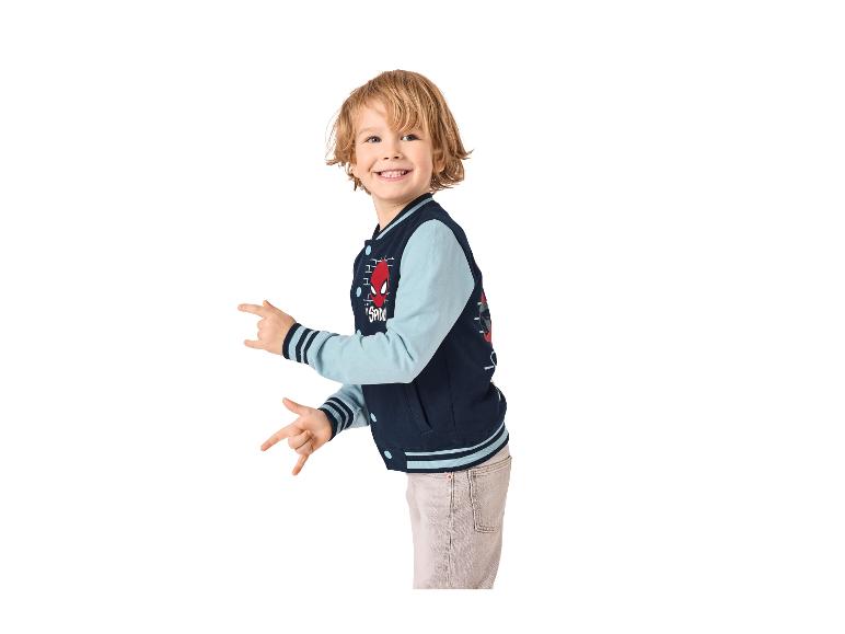 Garçon souriant dans une veste universitaire bleu foncé et bleu clair avec un design de super-héros.