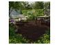 Terrasse en bois avec salon de jardin et table à manger, entourée de verdure et de fleurs.