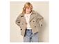 Femme en manteau court gris clair, pull blanc et jean.