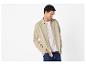 Homme en chemise beige et t-shirt blanc avec un jean.