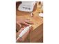 Personne utilisant un set de manucure électrique avec accessoires sur une table en bois.