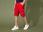 Homme portant un short cargo rouge avec le logo 'Miss Nature Company' et des baskets blanches.