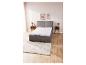 Un lit gris avec un matelas et un tapis dans une chambre à coucher.