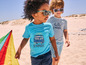 Deux garçons en vêtements d'été et lunettes de soleil sur la plage avec un cerf-volant.