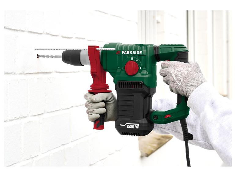 Perforateur vert et noir de 1550 W, perçant un mur de briques blanc.