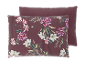 Deux oreillers, l'un avec un motif floral de magnolias et de pivoines sur fond rouge foncé.