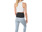 Femme en top blanc, leggings bleu clair et ceinture lombaire noire.
