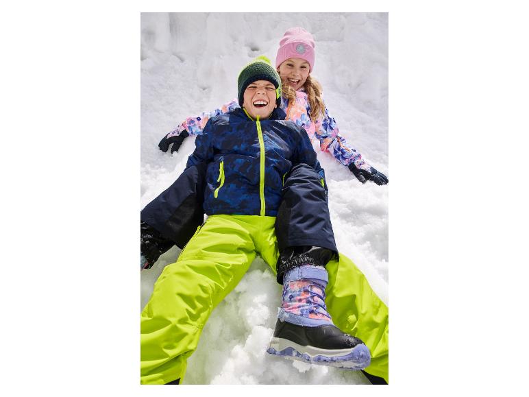 Deux enfants heureux en vêtements d'hiver colorés et bottes jouant dans la neige.