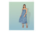 Une femme porte une robe en jean bleu et des sandales marrons.