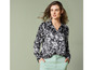 Une femme porte une chemise noire à imprimé floral blanc et un pantalon vert clair.