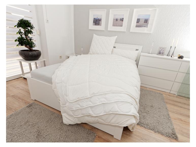 Chambre à coucher avec un lit blanc, literie, commode et un bonsaï.