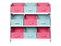 Rangement enfant en bois blanc avec des boîtes en tissu rose et bleu.