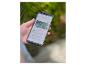 Main tenant un smartphone affichant une application domotique pour le contrôle de caméra de jardin.