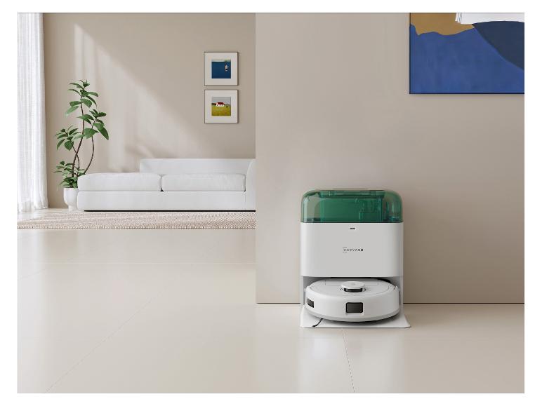 Robot aspirateur blanc avec station de charge verte dans un salon moderne.