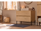 Meuble sous-vasque moderne en bois clair dans une salle de bain chaleureuse.