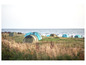 Des tentes sur une prairie avec vue sur la mer.