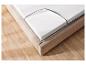 Un matelas en mousse sur un cadre en bois avec une tête de lit capitonnée.