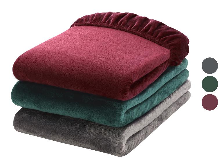 Pile de trois draps-housses en peluche bordeaux, vert foncé et gris