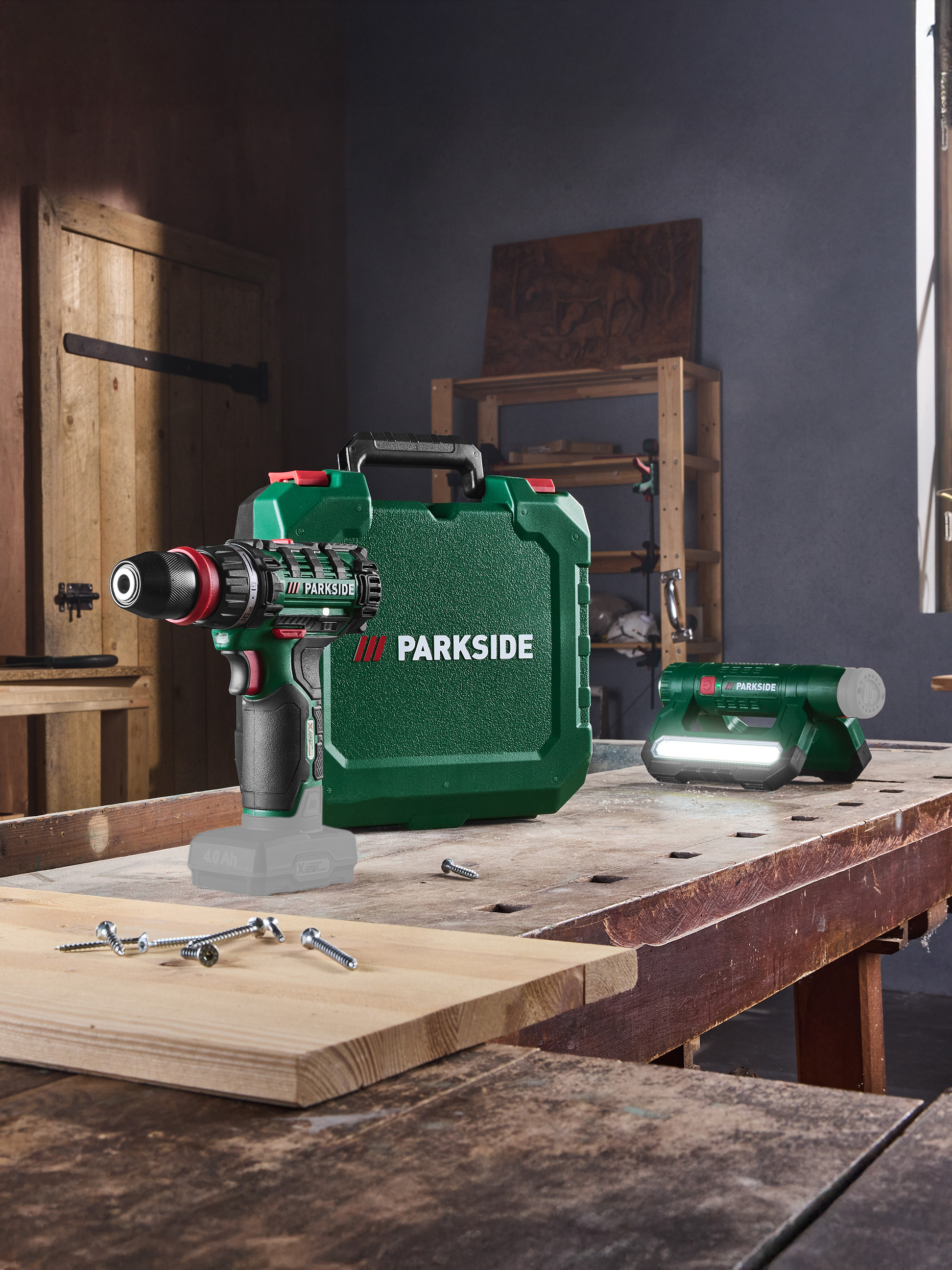 Perceuse sans fil, boîte à outils et lampe de travail sur un établi de menuisier avec des vis.